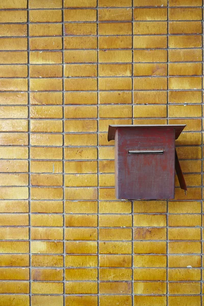 Žlutá dlaždice zeď s červeným rezavé postbox — Stock fotografie