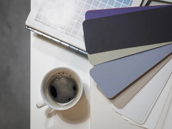 Cup of coffee on working table with color chart — Stock Photo, Image