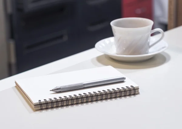 Café con libro y bolígrafo en mesa de oficina — Foto de Stock