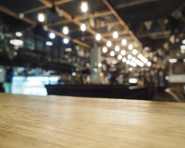 Parte superior de la mesa de madera con bar borrosa restaurante café fondo — Foto de Stock