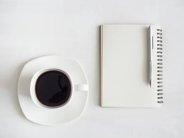 Café con cuaderno y pluma sobre fondo de tabla blanca — Foto de Stock