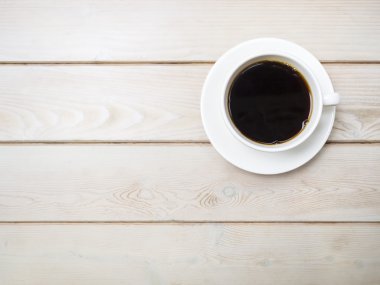 Tahta masa manzaralı bir fincan kahve.