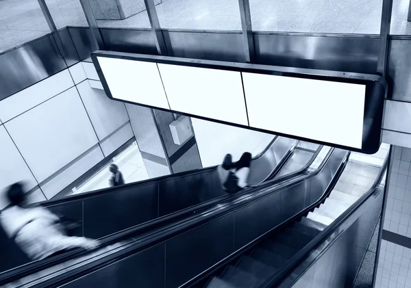 Boş afiş Billboard göstermek ile yürüyen merdiven ve insanlar metro istasyonu