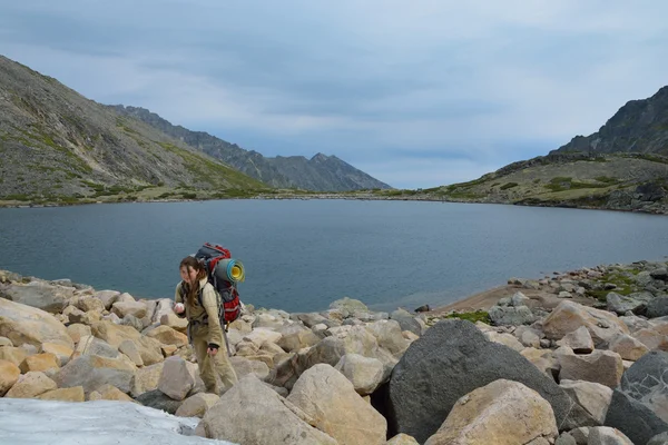 Chica turística comiendo nieve cerca de un lago de montaña en la cima de la — Foto de Stock