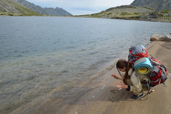 Девушка-туристка оставляет отпечатки рук на песчаном берегу горы — стоковое фото