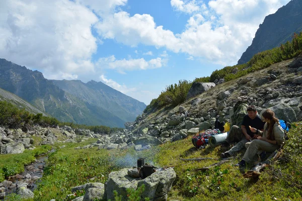 Un homme et une femme, touristes assis autour d'un feu de camp près de la r — Photo