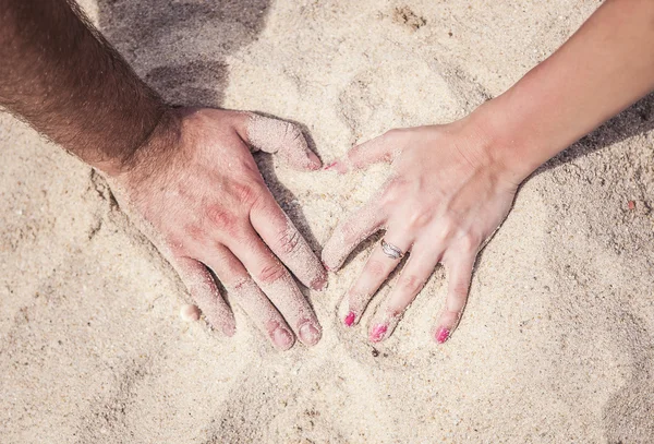 Mãos masculinas e femininas com anéis na areia Fotografias De Stock Royalty-Free