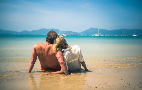 Älskande par på en tropisk strand mot havet — Stockfoto