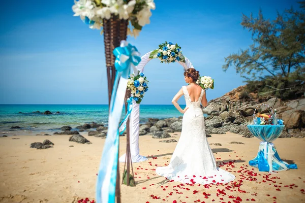 Счастливая девушка в свадебном платье на фоне свадебных арок на морском берегу — стоковое фото