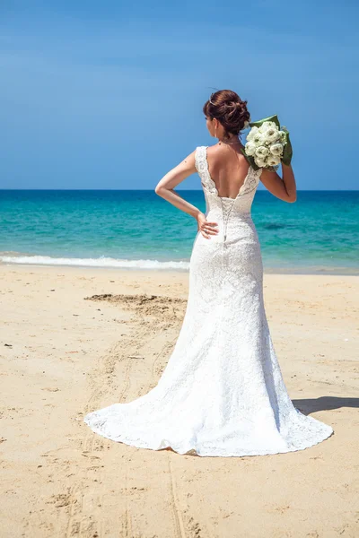 海辺の結婚式のアーチの背景にウェディング ドレスの女の子 — ストック写真