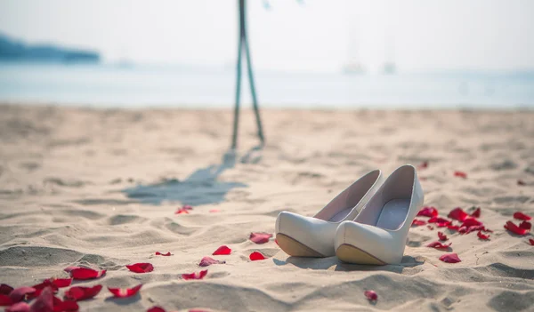 Womens bröllop skor på sanden i havet bakgrunden — Stockfoto