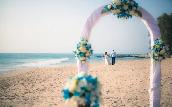 美丽的年轻夫妇在拱的婚礼是在沙滩上的海景 — 图库照片