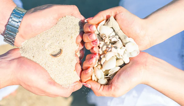 Man en vrouw met zand en schelpen koraal met een trouwring op het strand — Stockfoto