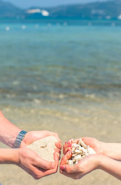 Man and woman holding sand and shells coral with a wedding ring on the beach — Stock Photo, Image