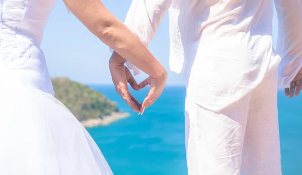 Händer i form av ett hjärta på bakgrund av havet — Stockfoto