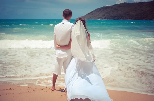 Pareja cariñosa en una playa tropical contra el fondo del mar puesta de sol del océano — Foto de Stock