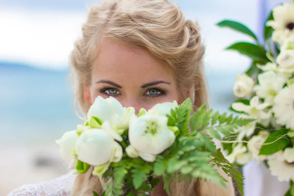 Happy beautiful girl in a wedding dress with a bouquet by the sea — Stock Photo, Image