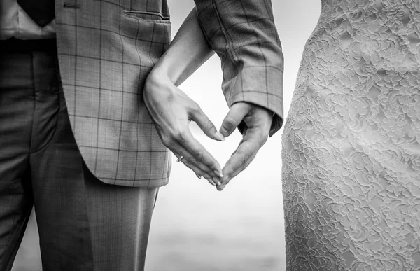 Hands in the shape of a heart on the background of the sea  Male and female hands with rings — Stock Photo, Image