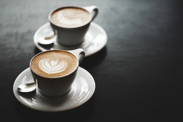 Two cups of cappuccino on black table — Stock Photo, Image