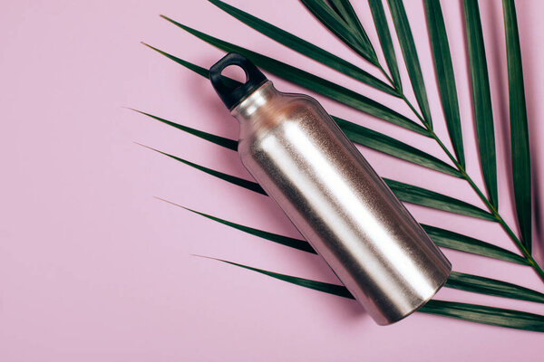 Zero waste bottle on palm leaf and pastel pink background