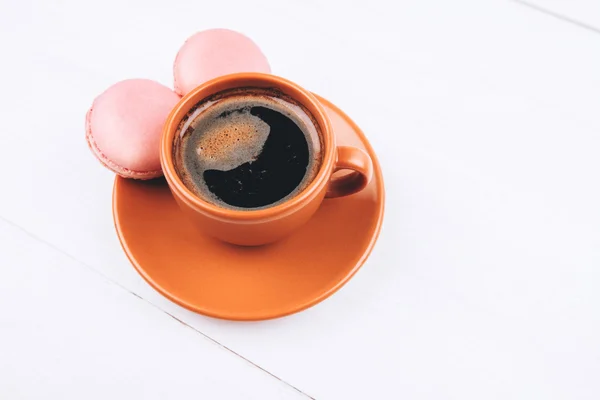 Pink macaroons with coffee on wooden background — Stock Photo, Image