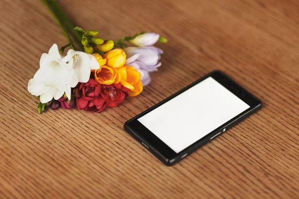 Smartphone und Blumen auf dem Tisch — Stockfoto