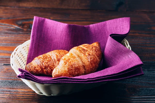 Croissants im Korb auf Holztisch — Stockfoto