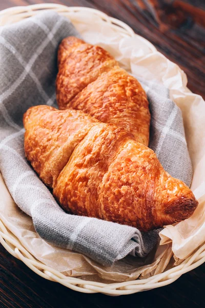 Croissants im Korb auf Holztisch — Stockfoto