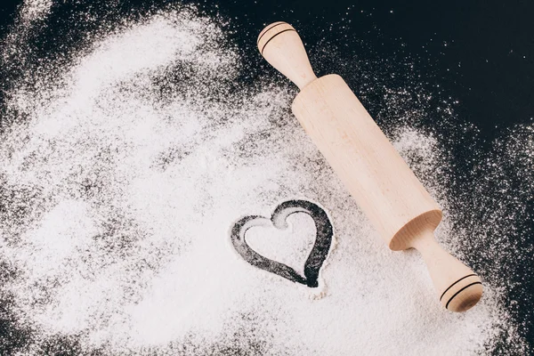 Flour with heart and rolling pin on black background — Stock Photo, Image