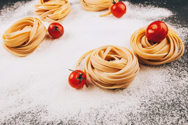 Pasta y tomates sobre harina — Foto de Stock
