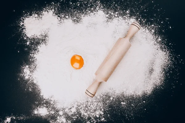Egg yolk and rolling pin on flour — Stock Photo, Image