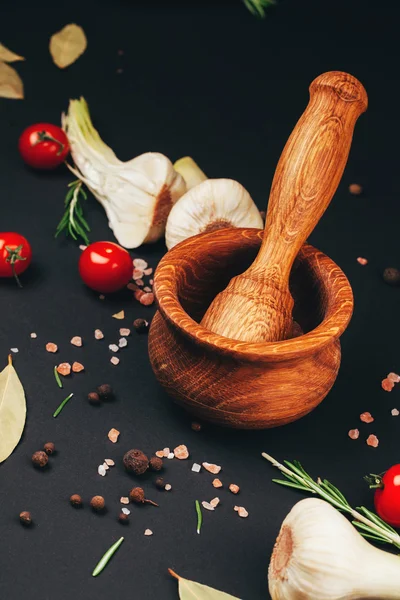 Tomatoes, herbs, spices and mortar on black background — Stock Photo, Image