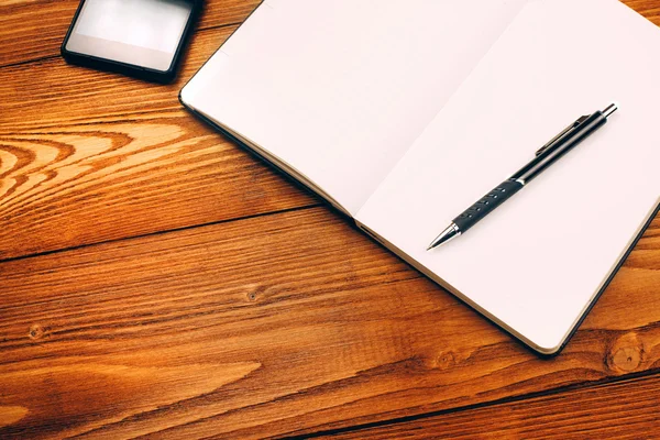 Table with notebook, smartphone and pen — Stock Photo, Image