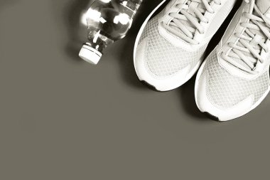 Beyaz spor ayakkabıları ve tek renkli arka planda temiz bir su şişesi. Formda ve sağlıklı yaşam tarzını temsil ediyor. 2026 'nın beyaz bulutlu dansçısı.