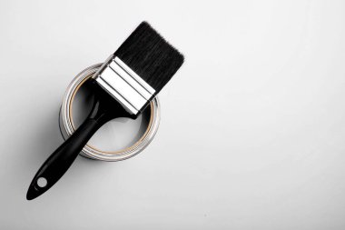 Üzerinde siyah bir fırça bulunan boya kutusu, üst perspektiften bakıldığında, ev gelişimini ve sönük projeleri temsil ediyor. 2026 'nın beyaz bulutlu dansçısı.