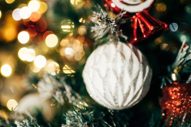 Noel ağacı süslemeler ve parlak ışıklarla süslenmiş, sıcak bokeh arka planlı neşeli bir tatil ortamı yaratıyor. Mutlu Noeller ve mutlu yıllar konsepti