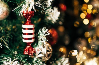 Kırmızı ve beyaz şeker kamışları, arka planda bulanık bokeh ışıkları olan yeşil bir Noel ağacını süslüyor. Mutlu Noeller ve mutlu yıllar konsepti