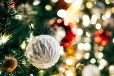 Noel süsü, sıcak, ışıltılı bokeh ışıklarıyla aydınlatılmış, yemyeşil bir ağaçta asılı duruyor. Tatil sezonu kutlaması. Mutlu Noeller ve mutlu yıllar konsepti