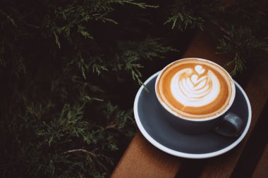 Ahşap masa üzerinde latte sanatıyla sulu kapuçino..