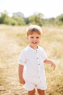 Gülümseyen genç bir çocuk güneşli bir açık hava ortamında duruyor, aile bütünlüğünü, çocukluk neşesini ve ebeveynlik bakımını somutlaştırıyor. Annelik, ebeveynlik ve günlük aile hayatı üzerine kampanyalar için mükemmel..