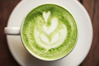 Fincan sütlü latte sanat, ahşap masa üzerinde duran matcha yeşil çay.