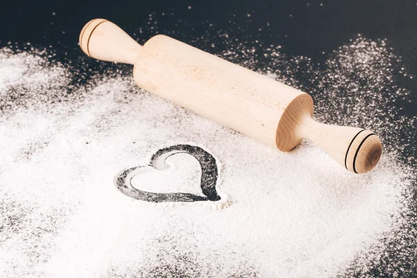 Flour with heart and rolling pin on black background — Stock Photo, Image