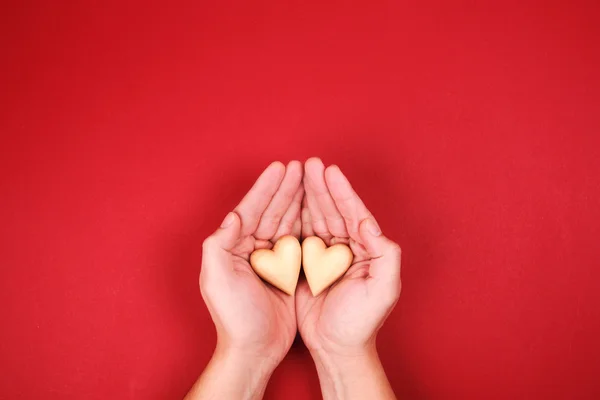 Two hands, holding little wooden heart genly — Stock Photo, Image