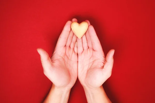 Two hands, holding little wooden heart genly — Stock Photo, Image