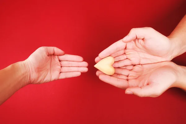 Männerhände schenken Frauenhand ein kleines Holzherz — Stockfoto