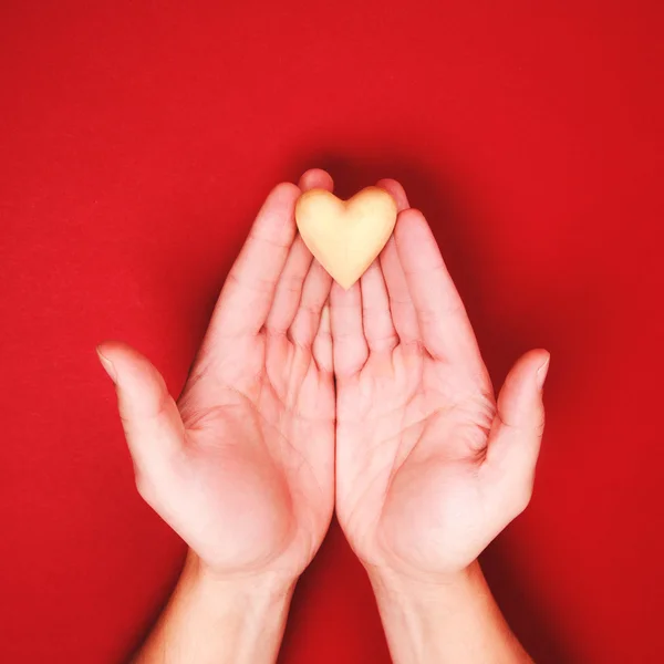 Two hands, holding little wooden heart genly — Stock Photo, Image