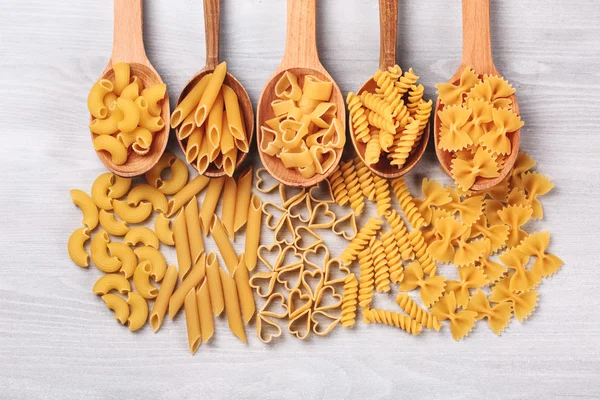Diferentes tipos de pasta acostada en cucharas de madera — Foto de Stock