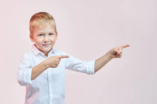 Sarışın, sevimli bir çocuk. İki eli ve parmakları yanda ve ileriye bakıyor..