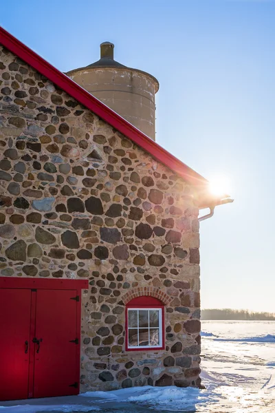 Velho celeiro de pedra com porta vermelha brilhante e Sunflare — Fotografia de Stock