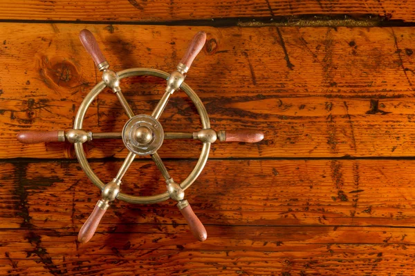 Brass Ship's Wheel on Textured Wood — Stock Photo, Image